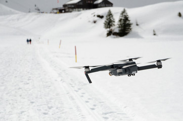 A camera drone hovering and flying over snowy skiing hills in alps