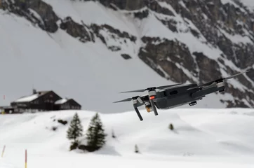 Fotobehang A camera drone hovering and spying over snowy skiing hills in alps © Maciej Gerszewski