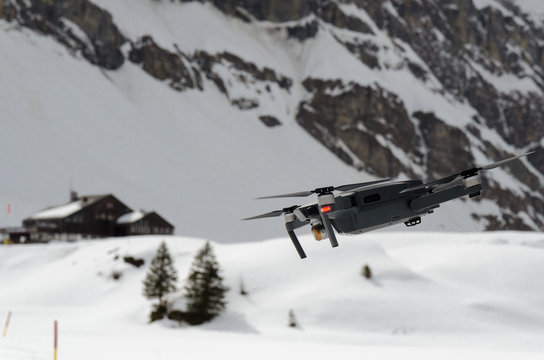 A camera drone hovering and spying over snowy skiing hills in alps