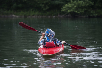 Boy teenager manages a canoe kayak on a wide river.