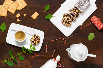 Tasty chocolate salami cookies with cup of espresso on rustic wooden background. Flat lay. 