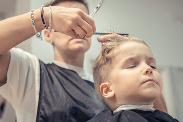 Obraz na płótnie Canvas Small boy during haircut at hair salon.