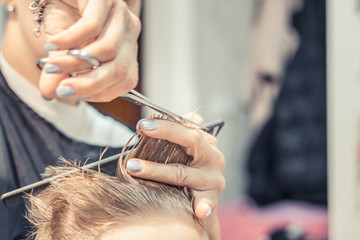 Obraz na płótnie Canvas Close up of hairstylist cutting boy's hair.