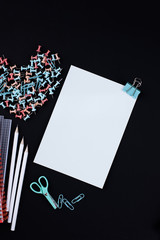 Many multi-colored paper clips and paper on a black background. Office concept. Subjects for the school. Copy space,
