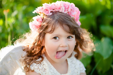 Cute little Angel girl with floral wreath, smiles and teases © Alinsa