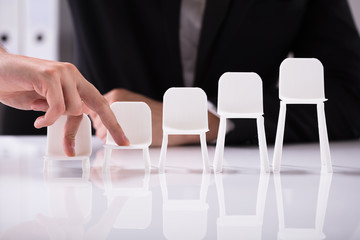 Businessperson Walking On Increasing Size Of Chairs With Finger