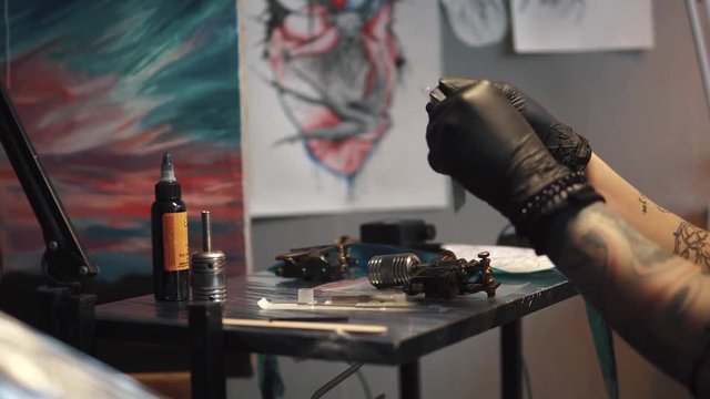 tattoo artist collects the tattoo machine. girl tattoo master prepares a rotary tattoo machine gun for drawing a drawing on the skin