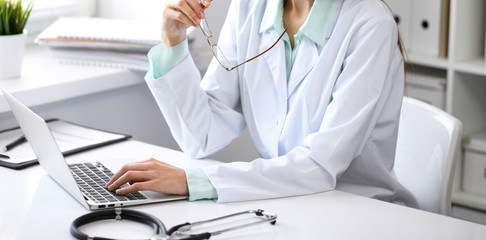 Close up of  unknown female doctor sitting  at the table near the window in hospital