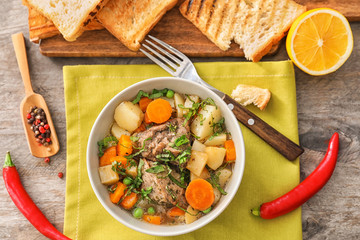 Bowl with tasty meat and potatoes on table