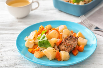Plate with tasty meat and potatoes on table