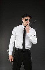 Obraz premium Male security guard using portable radio transmitter on dark background