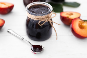 Jar with tasty plum jam on table
