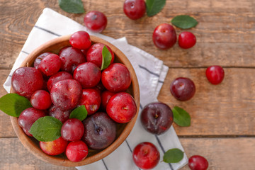 Naklejka na ściany i meble Bowl with ripe juicy plums on wooden table