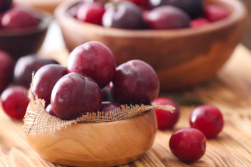 Bowl with ripe juicy plums on table