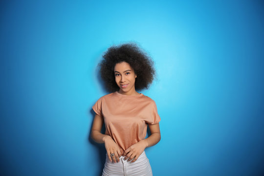 Attractive African-American woman posing on color background