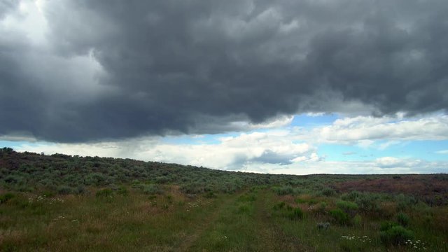 Dark storm clouds rolling through the sky over sagebrush in the Idaho desert.