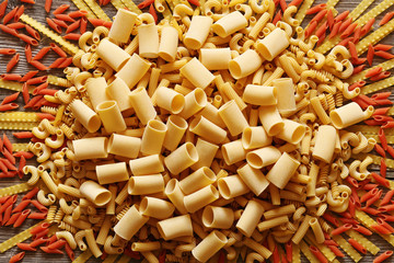 A lot of yellow and red big italian pasta on a wood background
