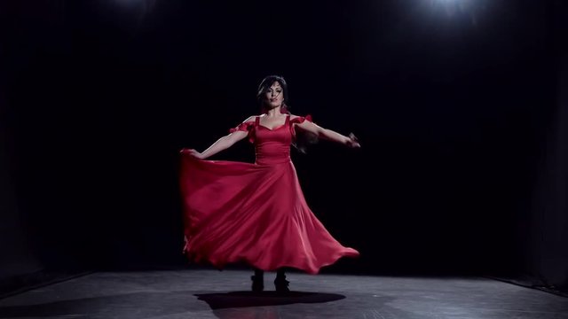 Woman in the dark room performs elegant movements dance. Black background