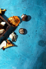 Wicker tray with variety of raw mushrooms on table.