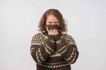 Woman in warm brown sweater hiding her face. Only eyes are seen. She wants to stay anonym.