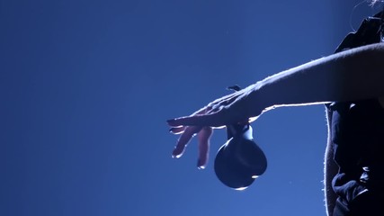 Girl is dancing in a hat with castanets in her hands dancing. Llight from behind. Dark background. Silhouette
