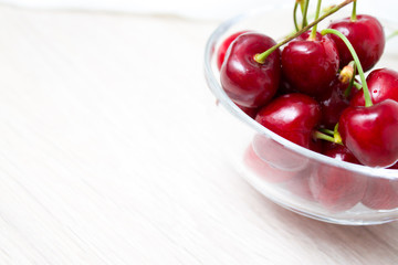 Cherries in glass dish. Cherry on wood and white background. - healthy eating and food concept