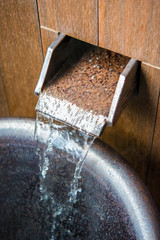 Faucet in Japanese style, water flows, Hanoke, Japan. Vertical. Close-up.