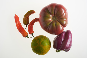 Multicolored tomatoes and peppers on white