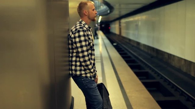 man with a backpack waiting for a train at a metro station