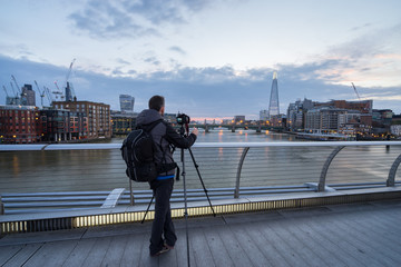 Cityscape photographer taking picture of London panorama at sunrise from Millennium bridge