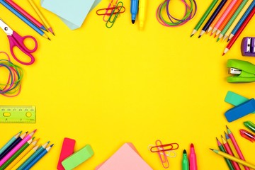 School supplies frame against a bright yellow paper background