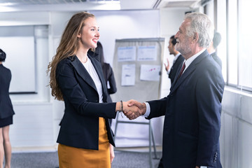 Business man and Business Woman shaking hands and discussion with colleague in meeting room or conference room and audience.