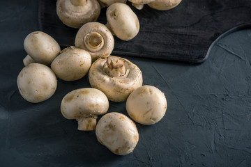 Champignons on the dark kitchen table. Cooking delicious dishes with mushrooms