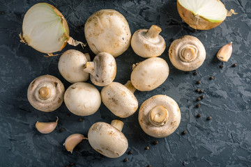 White Champions, spices and ingredients on the dark kitchen table. Concept of cooking mushroom dishes