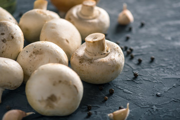 Fresh white Champions, spices and ingredients on the dark kitchen table. Concept of cooking mushroom dishes