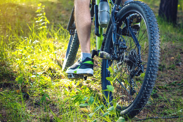Cyclist on a green mountain bike in the woods riding on the grass. Concept of active and extreme lifestyle