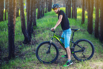 Man in a helmet riding on a green mountain bike in the woods. Cyclist in motion. Concept of active and healthy lifestyle