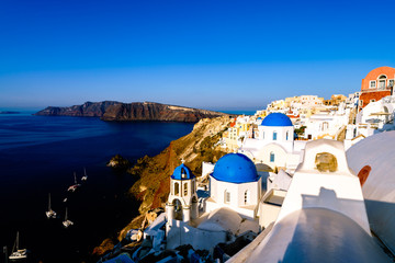 Fototapeta premium Morning light shines across blue domes of Santorini island, Cyclades, Greece