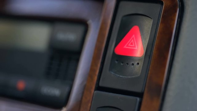 Male hand pressing emergency button in auto, stop by roadside, car accident