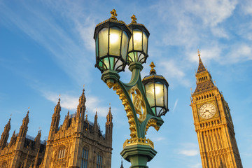 Fototapeta na wymiar Big Ben at bright morning sun with a traditional lamp post and rooftop of Westminster Palace in London, UK