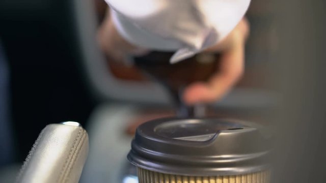 Man puts coffee into cup holder starting car, fast food for busy drivers closeup