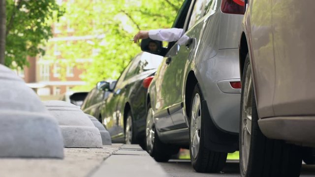 Man smoking in car, throwing stub of cigarette on pavement, bad manners, ecology