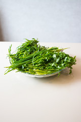 A bunch of greens and herbs. Green onion sprouts, cilantro, tarragon in glass bowl.