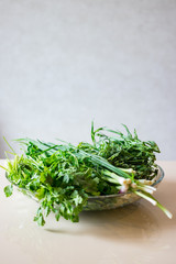 A bunch of greens and herbs. Green onion sprouts, cilantro, tarragon in glass bowl.