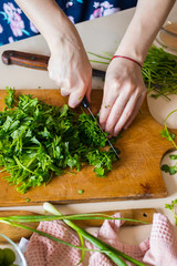 Woman hands cuts fresh herbs on wooden board preparing salad or lunch and dinner.  Raw vegan vegetarian healthy food. 