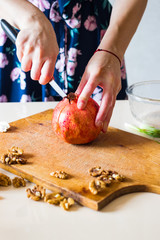 Woman hands peeling and carving pomegranate. Sweet asian fruit. Raw vegan vegetarian healthy food