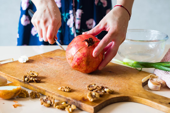 Woman hands peeling and carving pomegranate. Sweet asian fruit. Raw vegan vegetarian healthy food