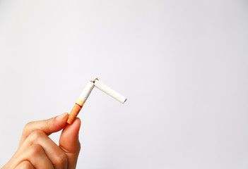 Broken cigarette in woman's hand, symbol of stop smoking.
