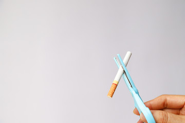 Closeup of cigarette with scissors in woman's hand, symbol of stop smoking.