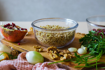 Grated, mixed and cut walnuts in glass bowl. Ingredient for Georgian traditional appetizer food - pkhali. Preparation process with garlic, pomegranate, cilantro, onion.